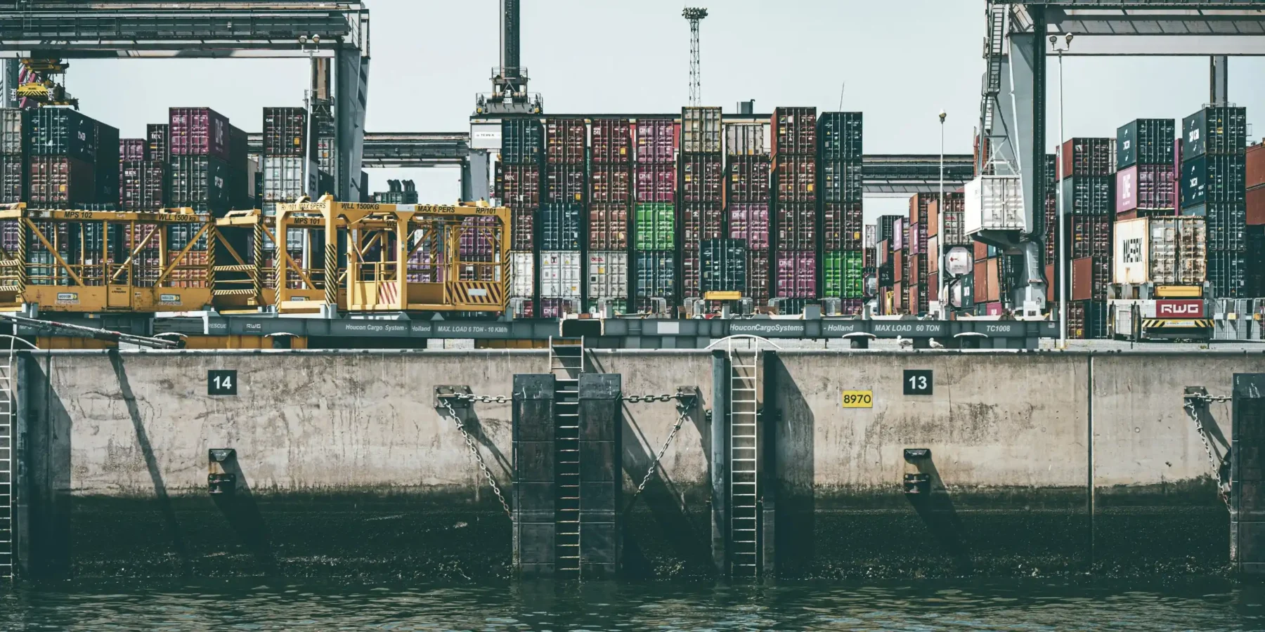 Muelle de un puerto con contenedores apilados detrás del agua