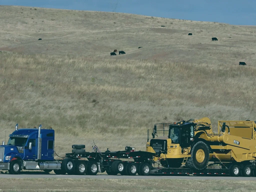 Tractocamión con cama baja transportando maquinaria pesada de construcción por carretera